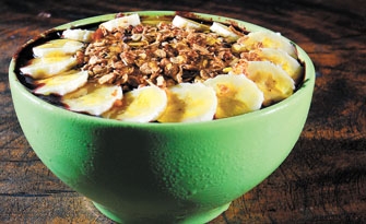 Na tigela muito açaí acompanhado de banana e granola